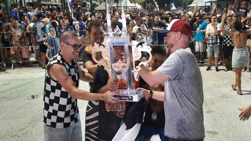 Equipe da escola de samba se reúne para levantar o troféu, na frente do público no Sambódromo de Uruguaiana